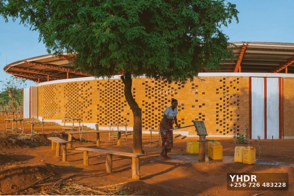 Woman Fetching Water At Brick Pavilion Borehole Pump. YHDR Builders Uganda Ltd carries out borehole drilling and construction.